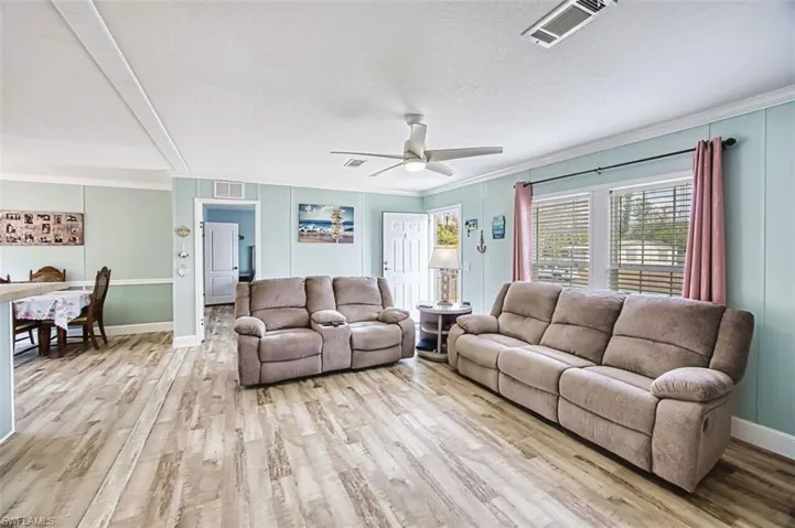 Living area with light wood-style flooring, a ceiling fan, and ornamental molding