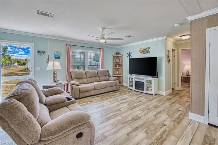 Living area featuring light wood-type flooring, crown molding, and ceiling fan