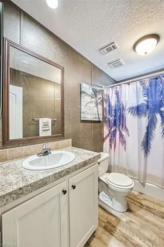 Full bathroom featuring vanity, a textured ceiling, and shower / bath combination with curtain