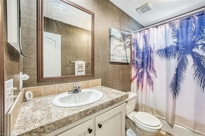 Bathroom with vanity, a textured ceiling, and curtained shower