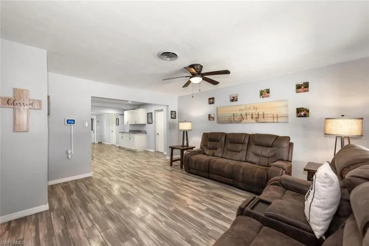 Living room with baseboards, visible vents, a ceiling fan, and wood finished floors