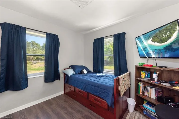 Bedroom featuring baseboards, visible vents, and wood finished floors