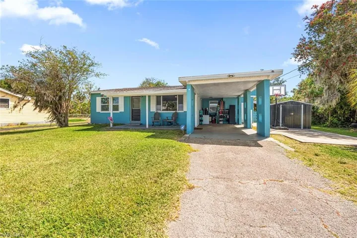 View of front of house with driveway, an attached carport, and a front yard