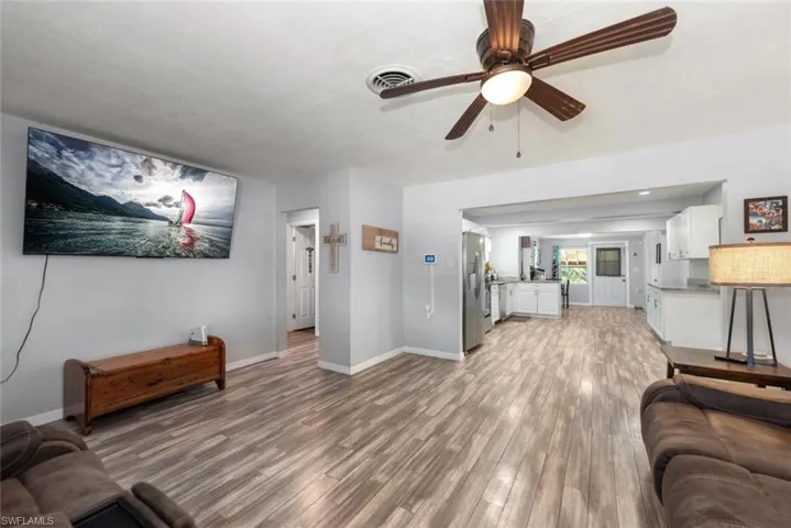 Living room featuring baseboards, ceiling fan, visible vents, and light wood-style floors
