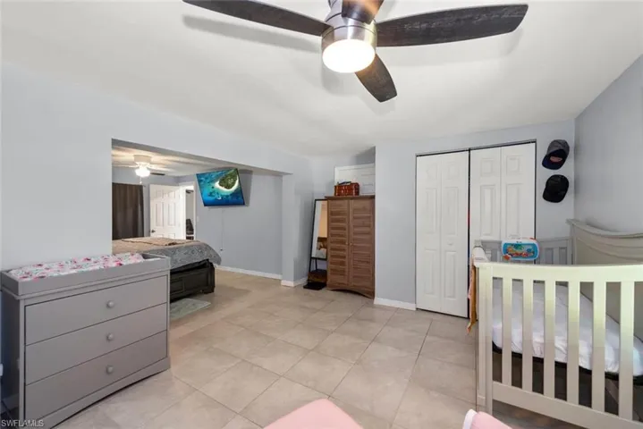 Bedroom featuring a ceiling fan, light tile patterned floors, baseboards, and a closet