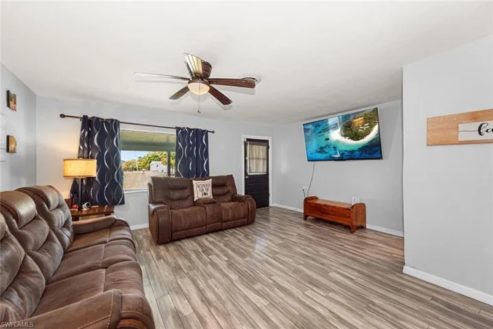Living room with light wood-type flooring, baseboards, and ceiling fan