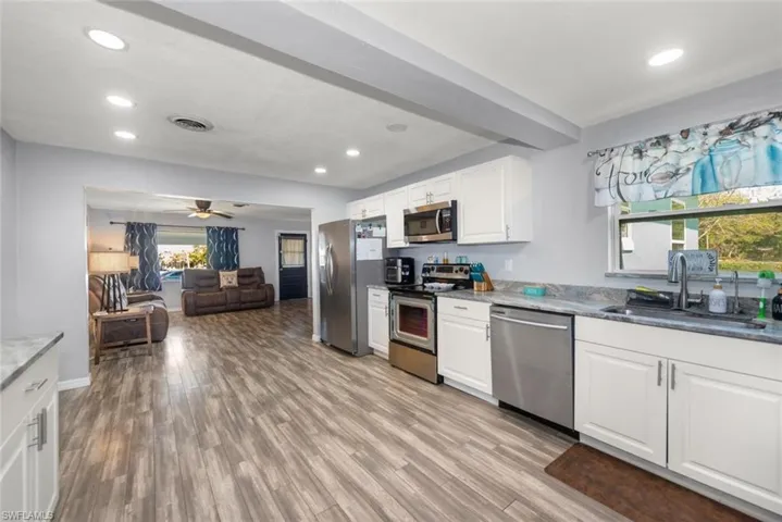 Kitchen featuring a sink, light wood finished floors, white cabinetry, stainless steel appliances, and visible vents