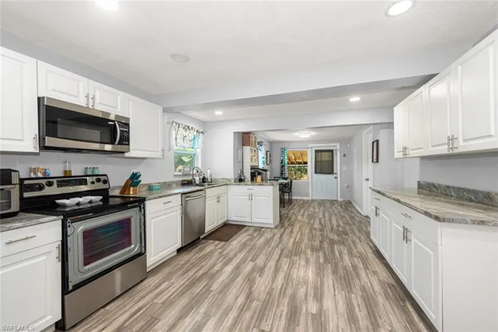Kitchen with white cabinets, light wood-style flooring, a peninsula, and appliances with stainless steel finishes