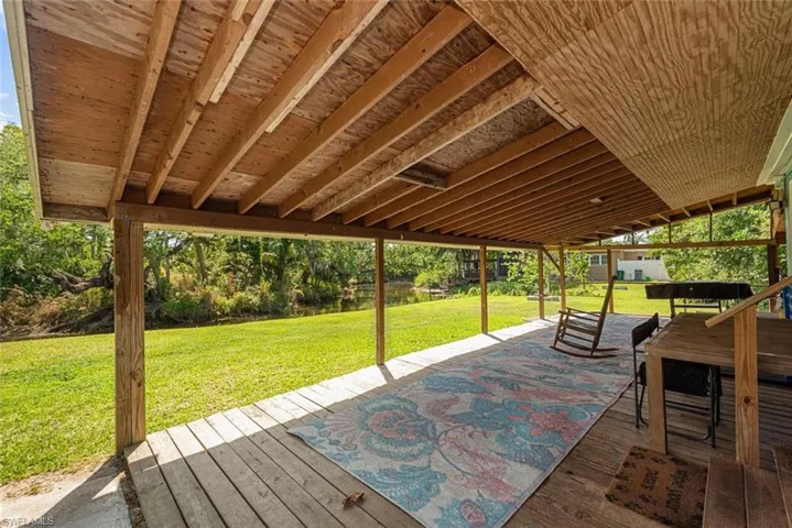 Wooden terrace with a patio and a yard