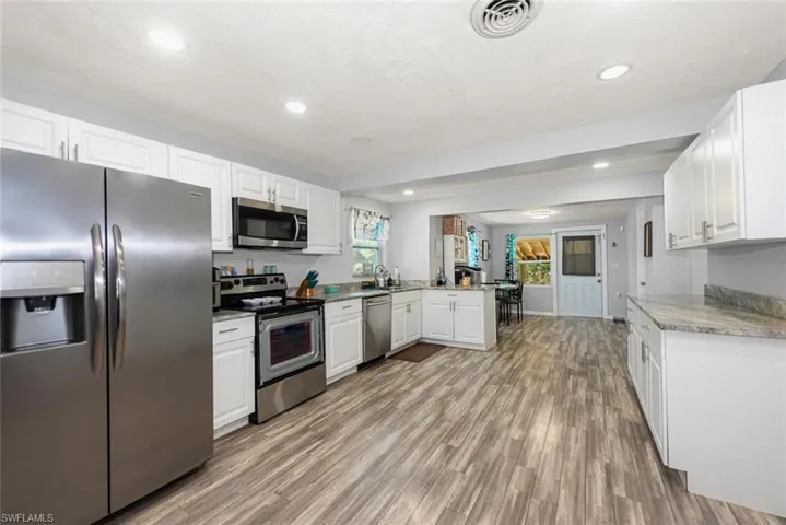 Kitchen with visible vents, a peninsula, plenty of natural light, light wood finished floors, and stainless steel appliances