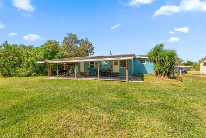 Rear view of house featuring a lawn and a carport