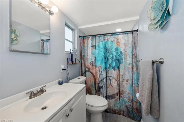 Full bath featuring curtained shower, toilet, and vanity