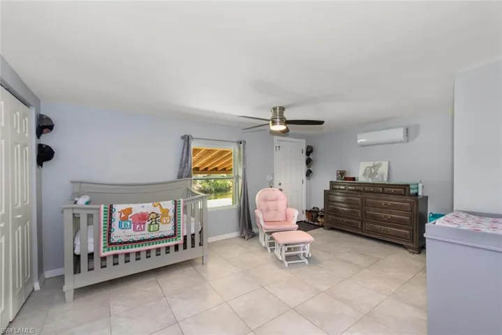 Bedroom with a closet, a wall mounted AC, baseboards, ceiling fan, and tile patterned floors