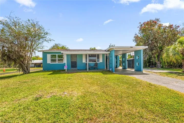 View of front facade with a porch, an attached carport, driveway, and a front lawn