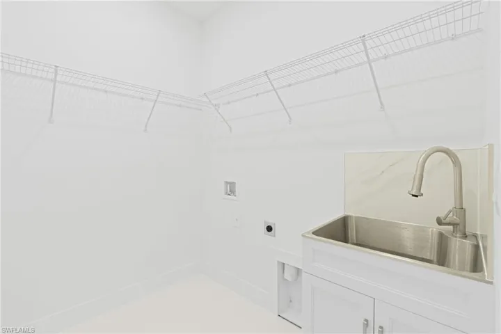 Washroom with sink, cabinets, hookup for an electric dryer, and washer hookup