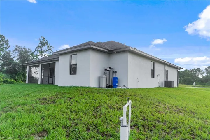 View of side of property featuring central air condition unit and a yard