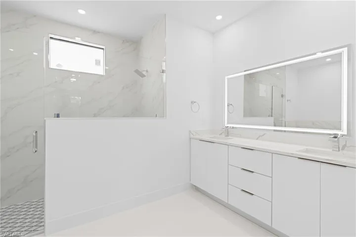 Bathroom with dual vanity, tile patterned flooring, and walk in shower