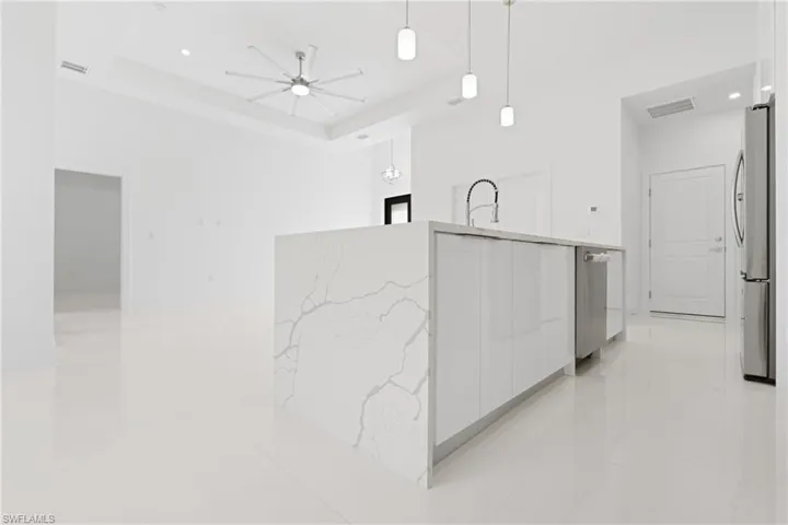 Kitchen featuring light tile patterned flooring, white cabinetry, appliances with stainless steel finishes, and a tray ceiling