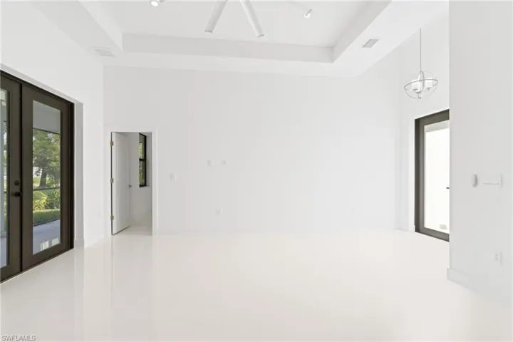Unfurnished room with an inviting chandelier, tile patterned flooring, and a raised ceiling