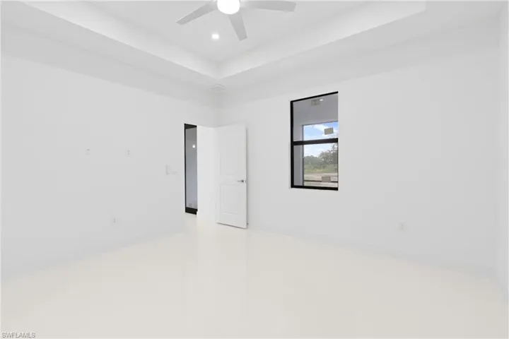 Tiled spare room featuring ceiling fan and a tray ceiling