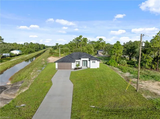 View of front facade featuring a water view, a garage, and a front yard