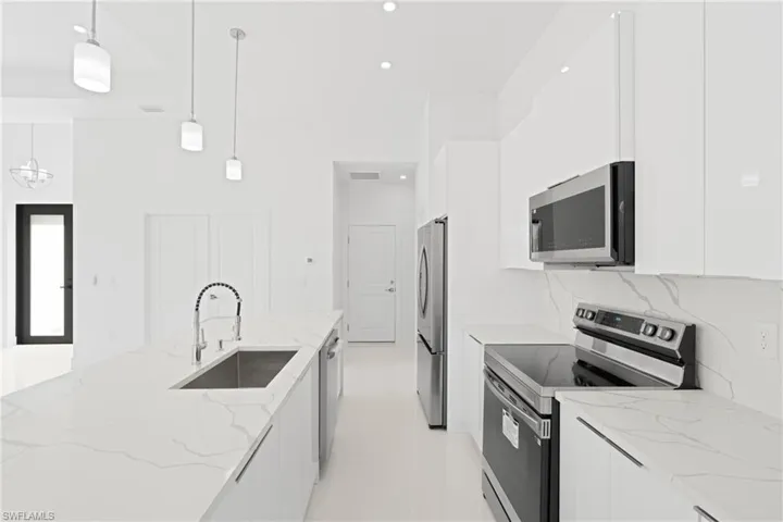 Kitchen featuring sink, appliances with stainless steel finishes, white cabinets, and light tile patterned floors