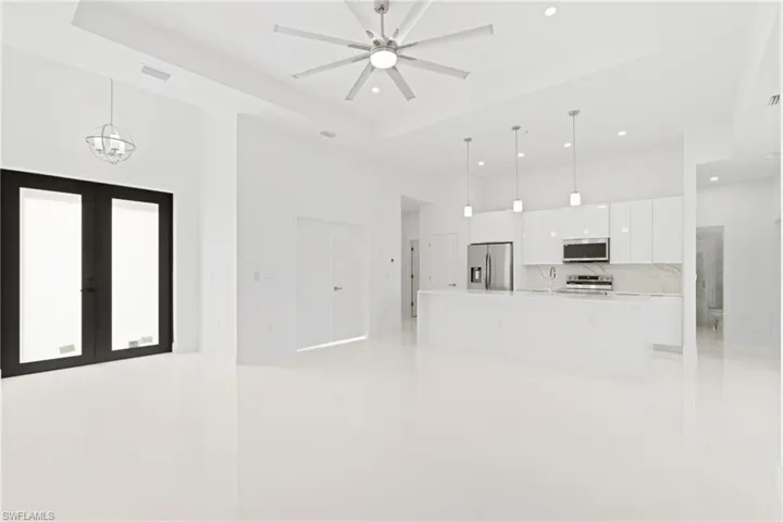 Unfurnished living room with a towering ceiling, a raised ceiling, light tile patterned floors, and ceiling fan