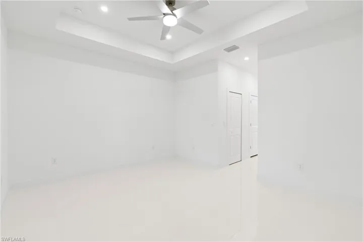 Empty room with tile patterned floors, a raised ceiling, and ceiling fan