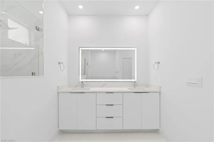 Bathroom featuring double vanity, tile patterned flooring, and tiled shower