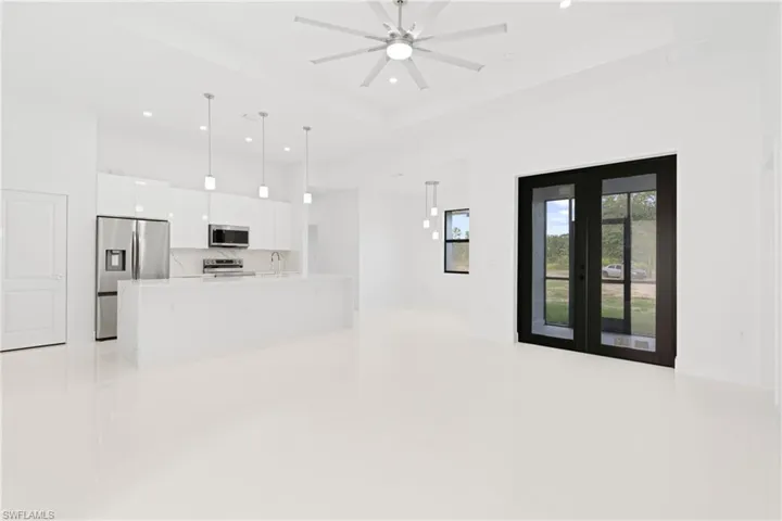 Unfurnished living room featuring sink, french doors, a raised ceiling, and ceiling fan