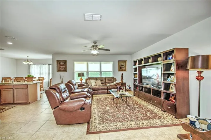 Tiled living room featuring ceiling fan with notable chandelier
