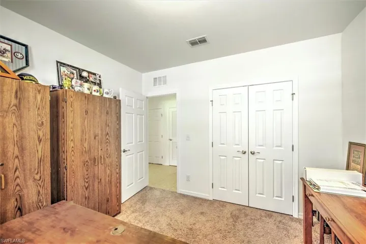 Bedroom with light carpet and a closet