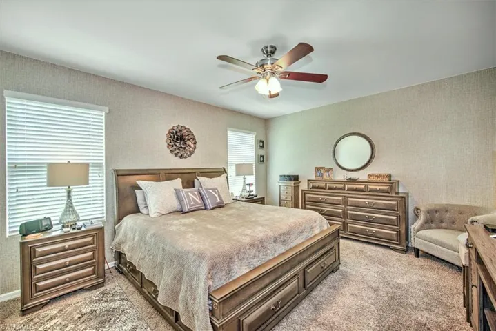 Carpeted bedroom with multiple windows and ceiling fan