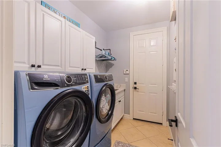 Clothes washing area with cabinets, light tile patterned flooring, and independent washer and dryer