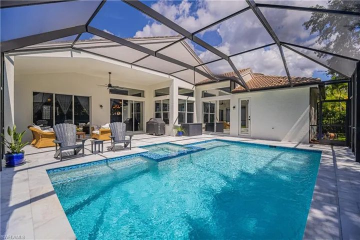 View of swimming pool with area for grilling, a patio area, ceiling fan, and glass enclosure