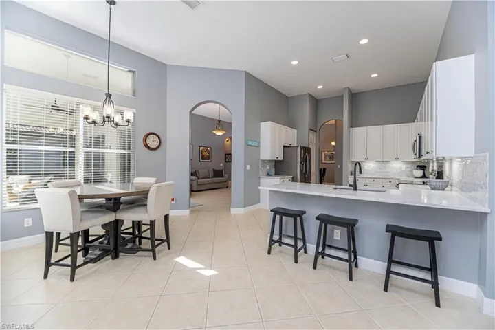 Kitchen featuring white cabinetry, decorative backsplash, stainless steel fridge with ice dispenser, sink, and kitchen peninsula