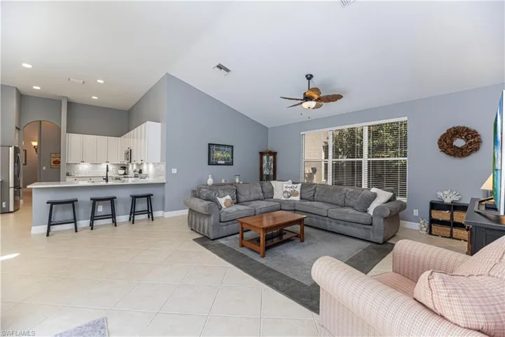 Tiled living room featuring high vaulted ceiling and ceiling fan