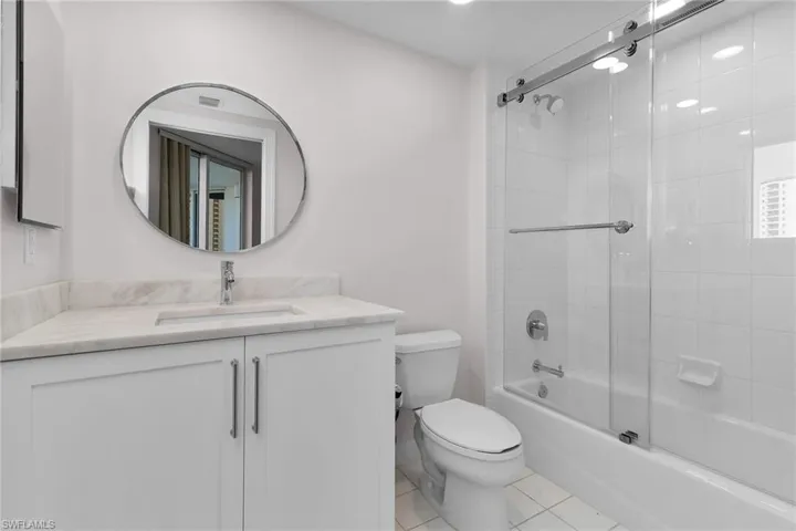 Full bathroom with bath / shower combo with glass door, light tile patterned floors, and vanity