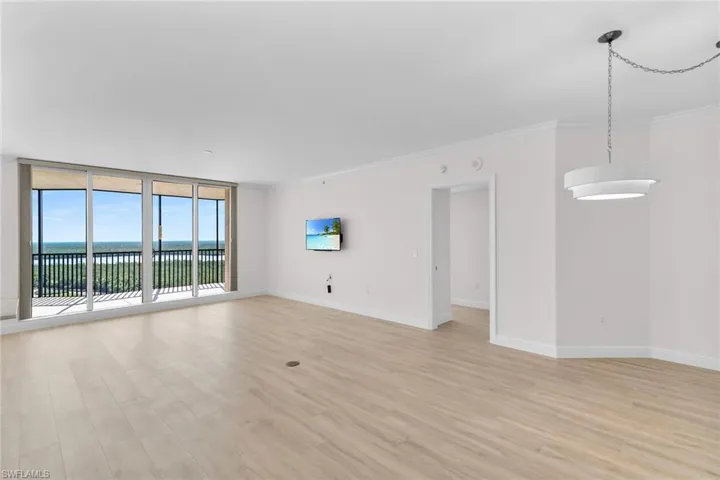 Unfurnished living room featuring light wood-type flooring, crown molding, and floor to ceiling windows