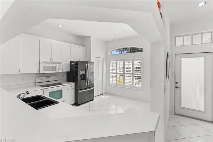 Kitchen with light countertops, white appliances, white cabinetry, light tile patterned floors, and recessed lighting