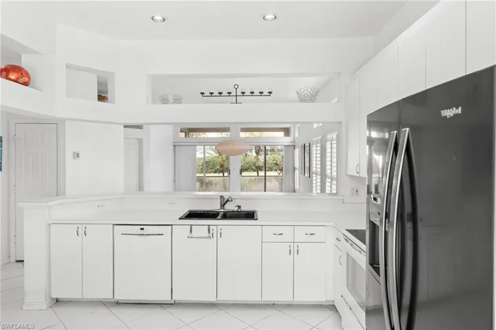 Kitchen with white appliances, white cabinetry, light countertops, a peninsula, and pendant lighting
