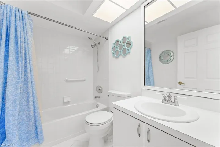 Full bathroom featuring vanity, shower / tub combo with curtain, and light tile patterned flooring
