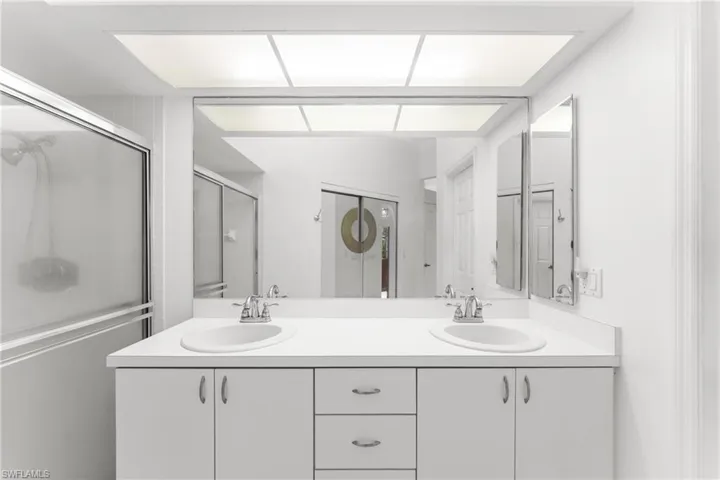 Bathroom featuring double vanity and a shower with door