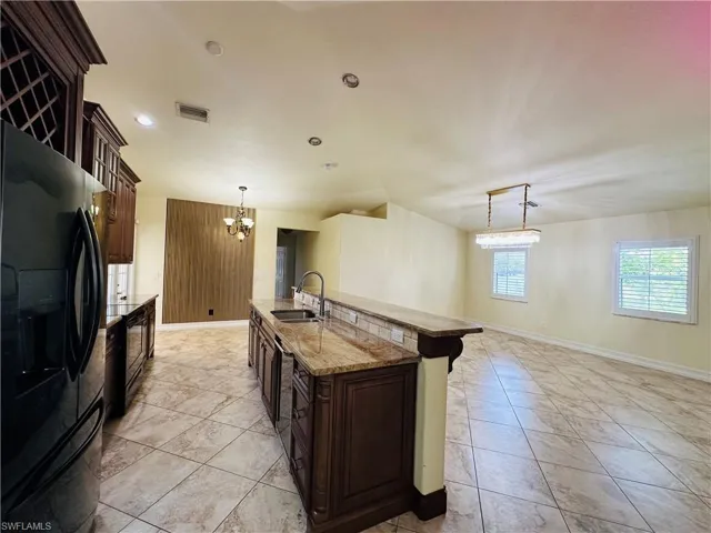 Kitchen featuring black fridge, a notable chandelier, sink, and light tile patterned floors
