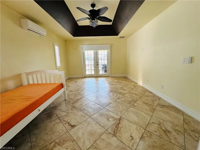 Spare room with ceiling fan, a raised ceiling, tile patterned floors, and a wall mounted air conditioner