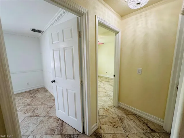 Hall with light tile patterned flooring and ornamental molding