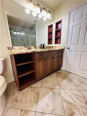 Bathroom featuring toilet, a tile shower, vanity, and tile patterned floors