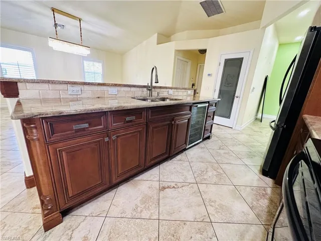 Kitchen with decorative backsplash, light tile patterned floors, sink, rail lighting, and decorative light fixtures