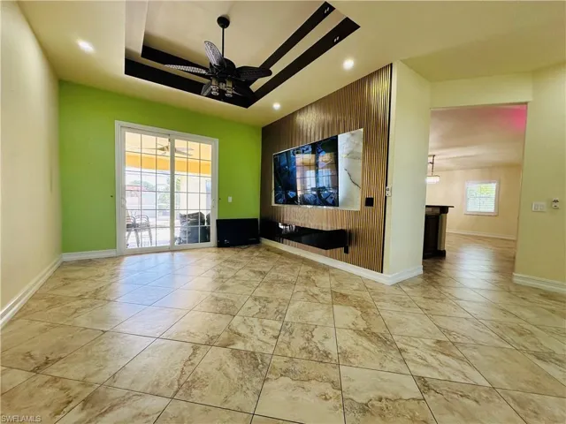 Unfurnished living room with a tray ceiling, ceiling fan, and light tile patterned flooring