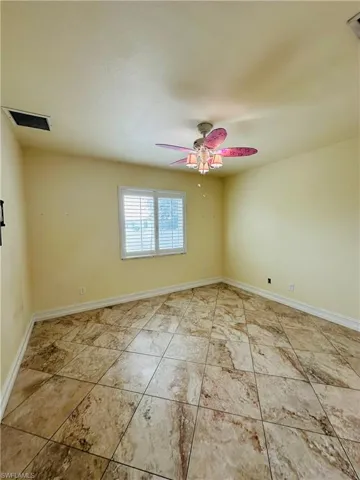 Empty room featuring ceiling fan and light tile patterned floors